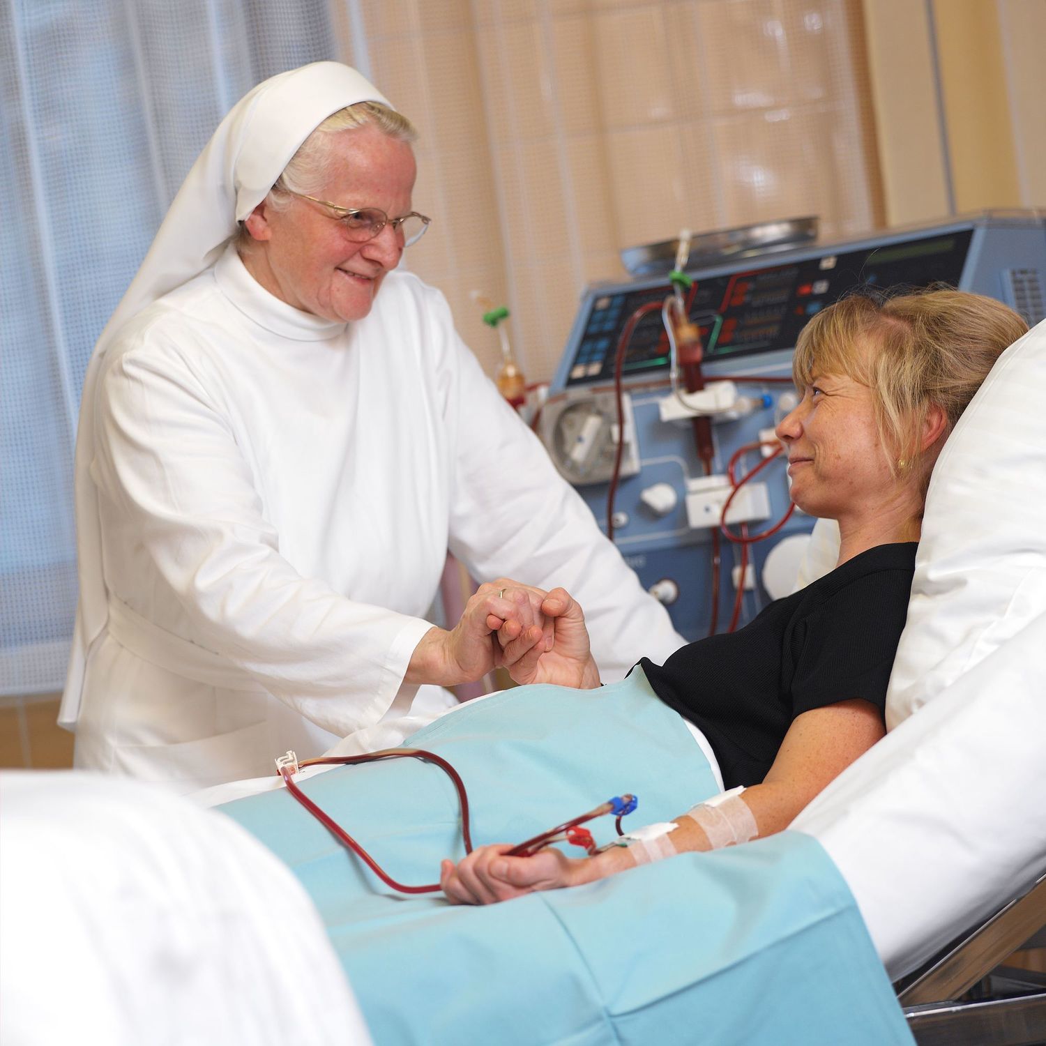 Dieses Bild zeigt eine Ordensschwester im Gespräch mit einer Patientin