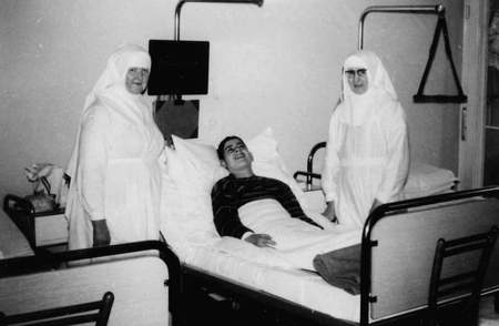 Die Schwestern Sr. Antonie und Sr. Margarete an einem Krankenbett. 