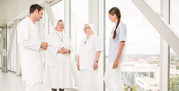Dieses Bild zeigt Ordensschwestern im Gespräch mit Krankenhauspersonal