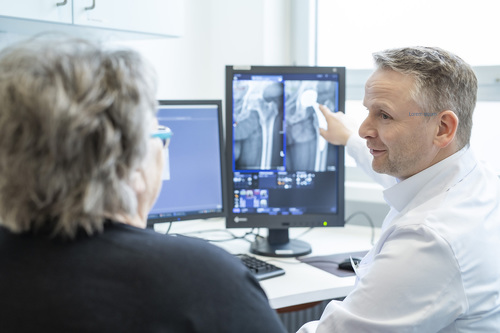 Das Bild zeigt einen Arzt bei der Besprechung von Befunden.